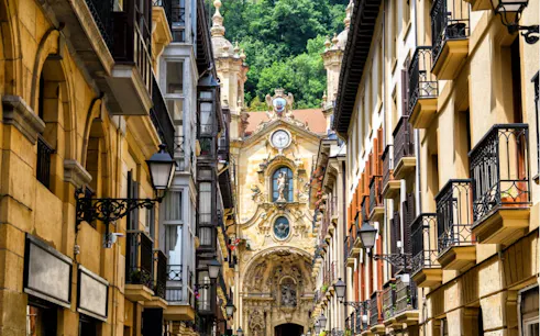 Narrow street in San Sebastian with view of Baroque church facade.