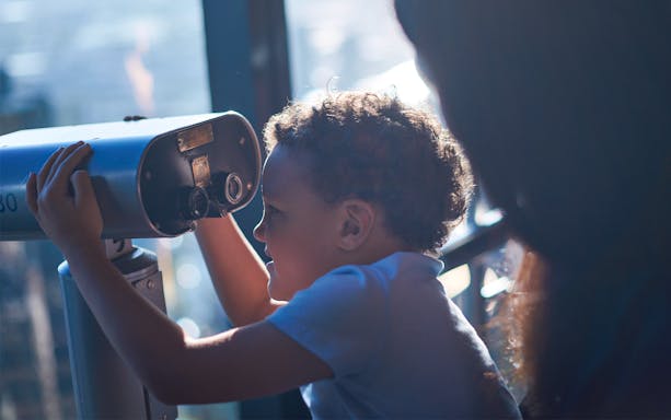 Child looking through a telescope at Melbourne Skydeck.