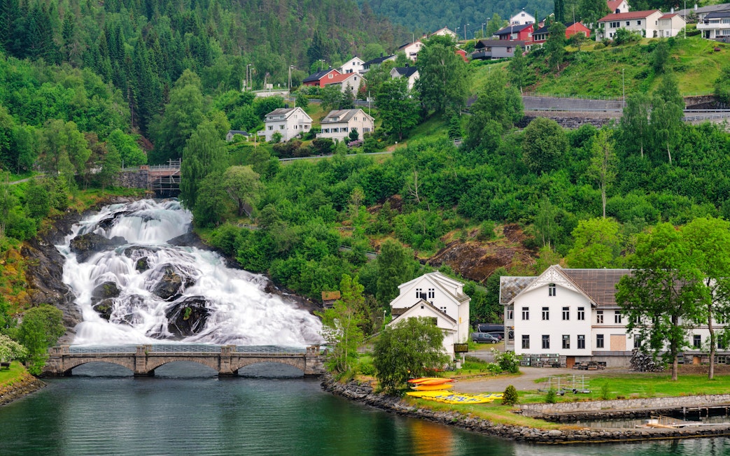 Hellesylt waterfall cascading near village houses in Norway.