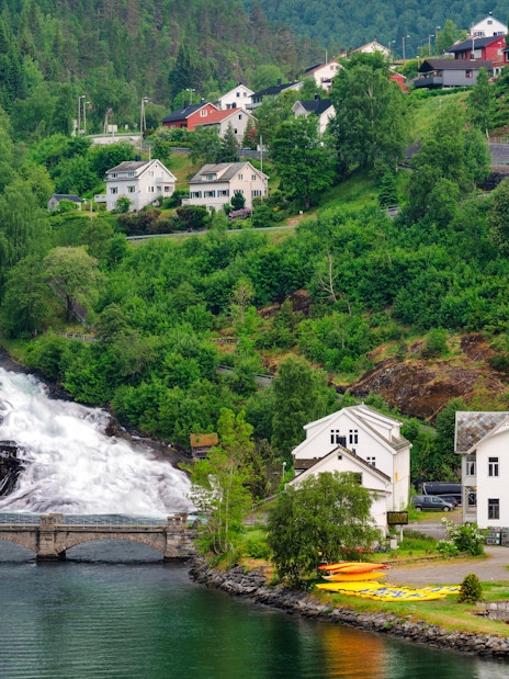 Hellesylt waterfall cascading near village houses in Norway.