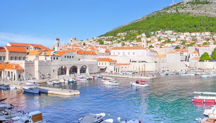 Old Port of Dubrovnik with boats and historic stone buildings under a clear sky.