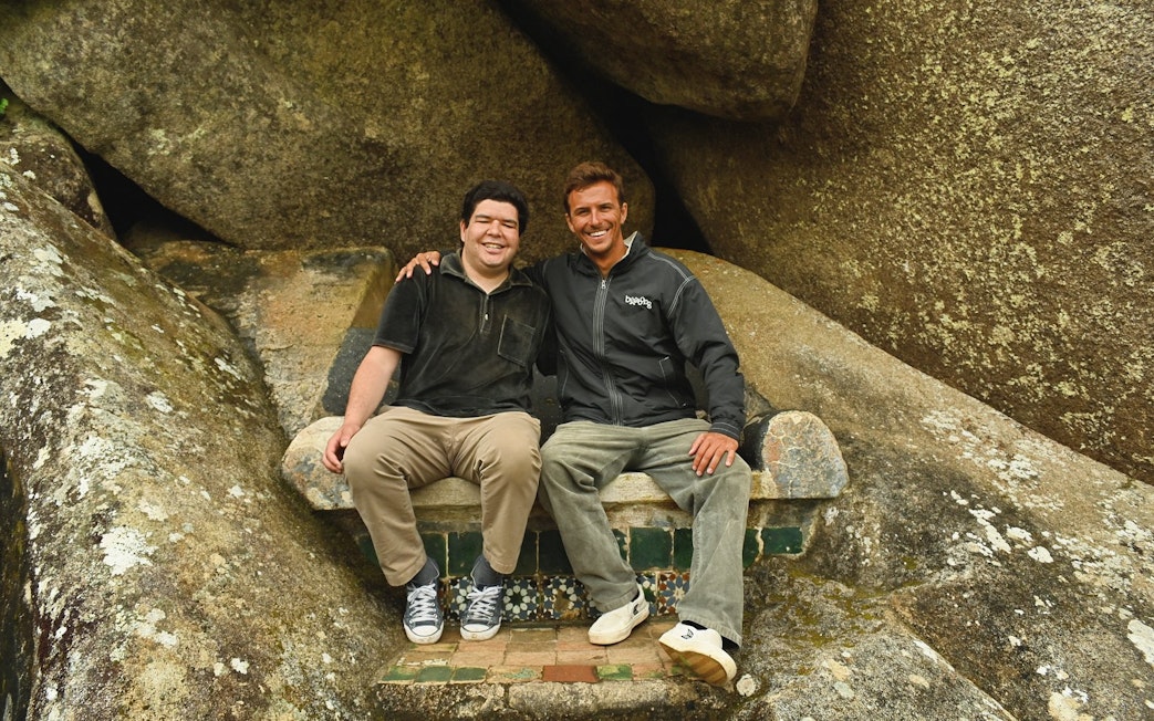 Tourists sitting on a stone bench surrounded by large rocks.