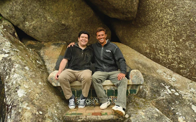 Tourists sitting on a stone bench surrounded by large rocks.