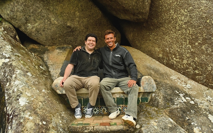 Tourists sitting on a stone bench surrounded by large rocks.