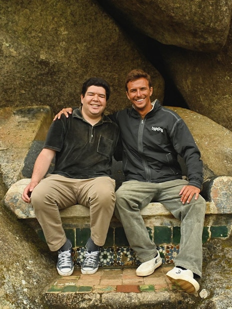 Tourists sitting on a stone bench surrounded by large rocks.