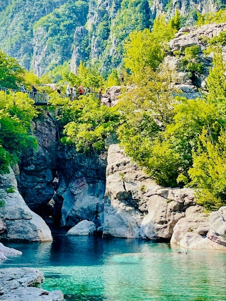 Blue Eye spring surrounded by lush greenery and rocky cliffs in Albania.