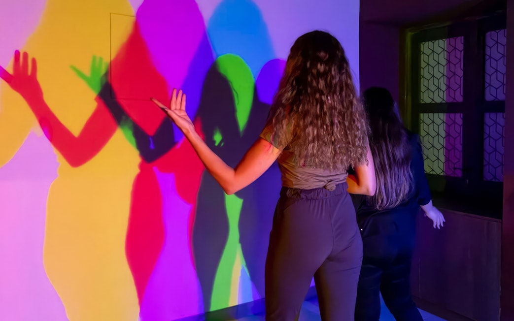 Visitors interacting with colorful light shadows at Museum of Illusions Dubai.