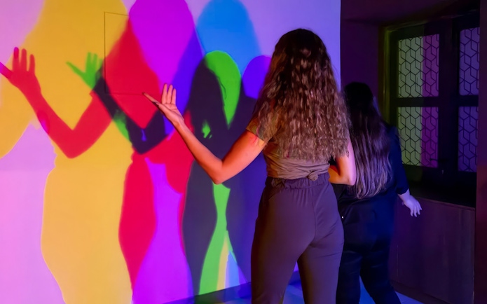 Visitors interacting with colorful light shadows at Museum of Illusions Dubai.