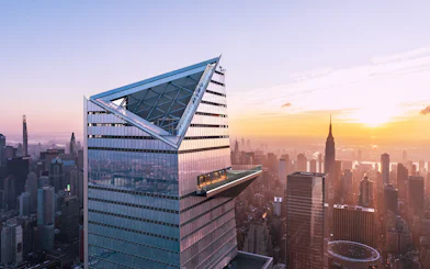 Visitors on Edge Observation Deck with New York City skyline at sunset.