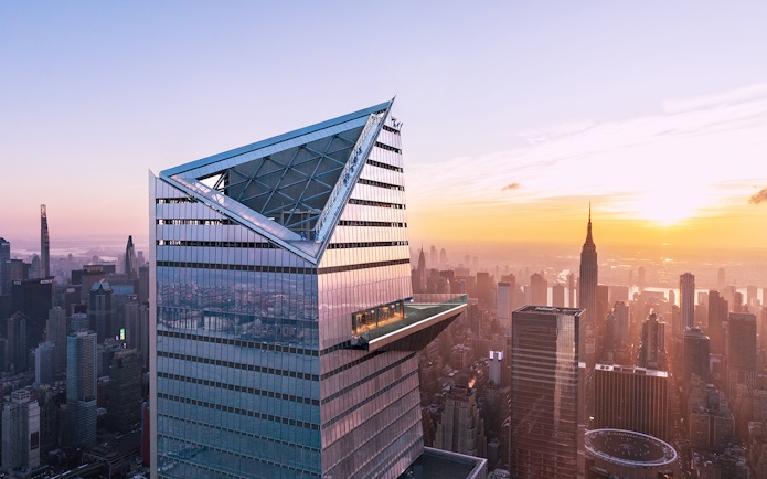 Visitors on Edge Observation Deck with New York City skyline at sunset.