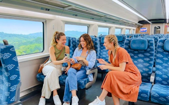 Travelers enjoying a train ride from Jakarta to Bandung with scenic views outside.