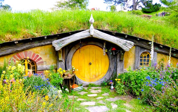Hobbit house with yellow door and garden at Hobbiton movie set tour.