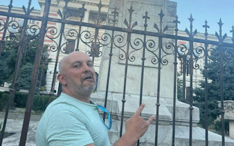 Man gesturing near an ornate fence in Bucharest during a self-guided city exploration game.