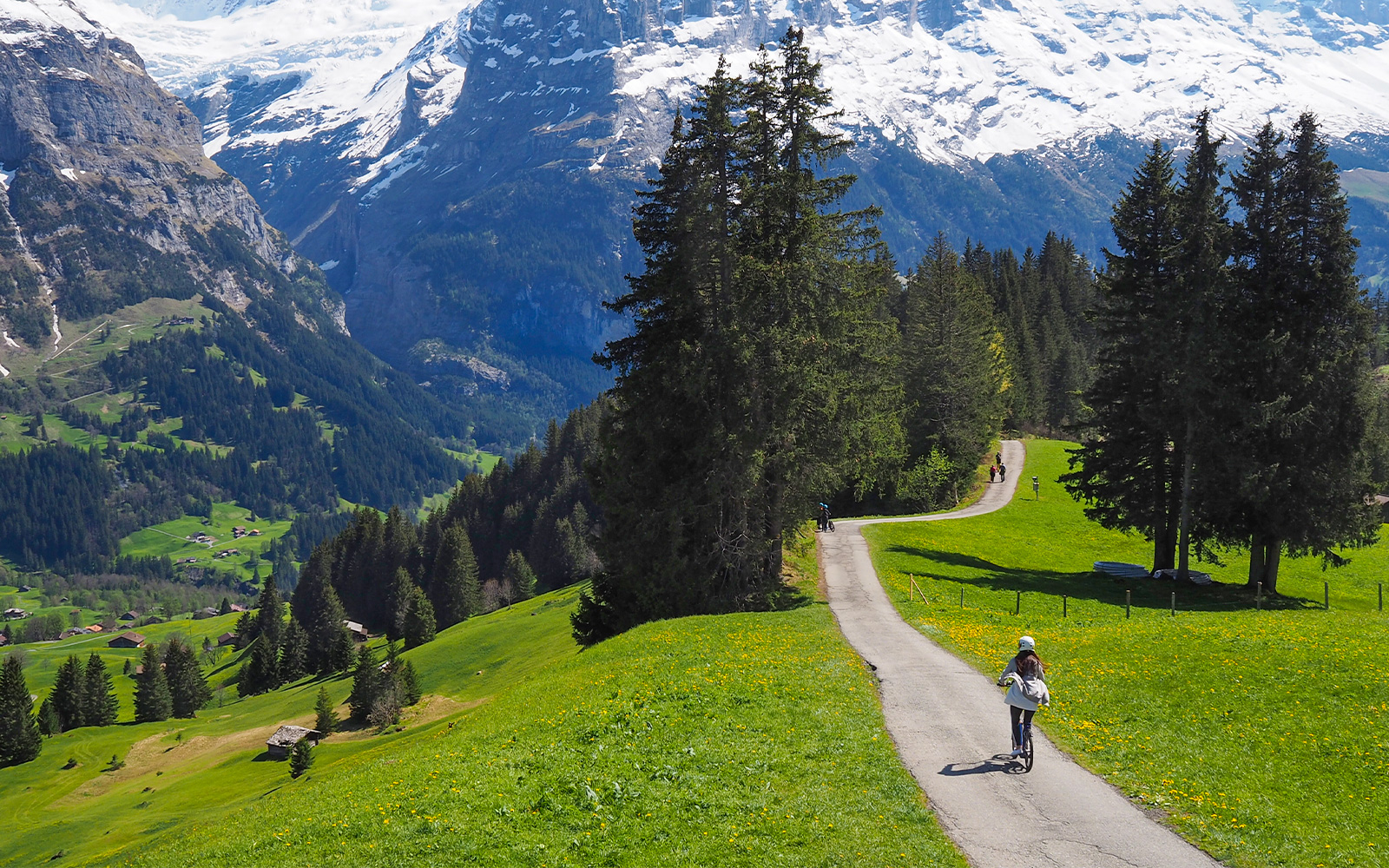 Person riding a Trottibike on a scenic path in Grindelwald with mountain views.