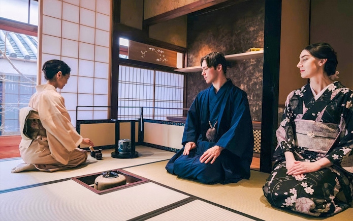 Tourists in kimono participating in a traditional Japanese tea ceremony.