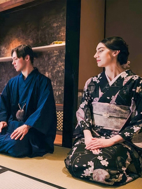 Tourists in kimono participating in a traditional Japanese tea ceremony.