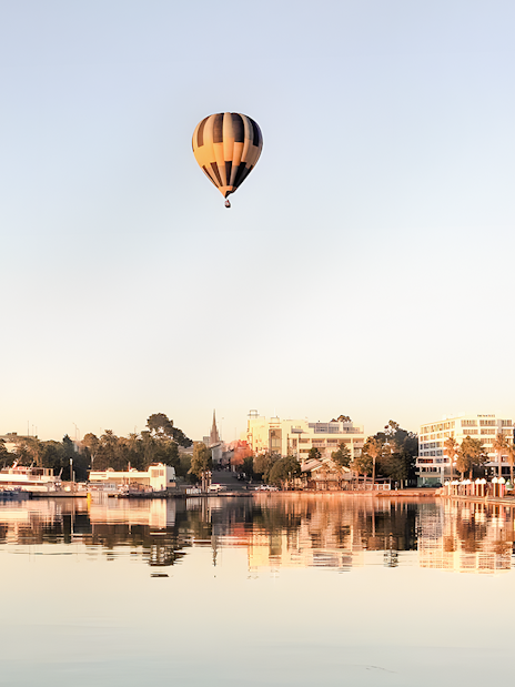Hot air balloon over cityscape near water, Great Ocean Balloon flight.