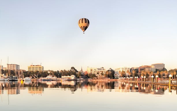 Hot air balloon over cityscape near water, Great Ocean Balloon flight.
