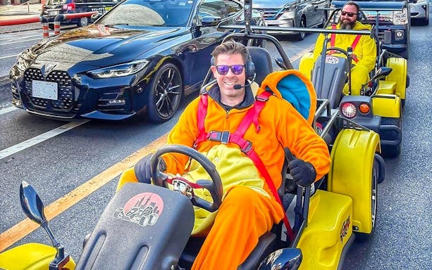 Go-kart riders in costumes on Tokyo street during Skytree, Ginza, and Imperial Palace tour.