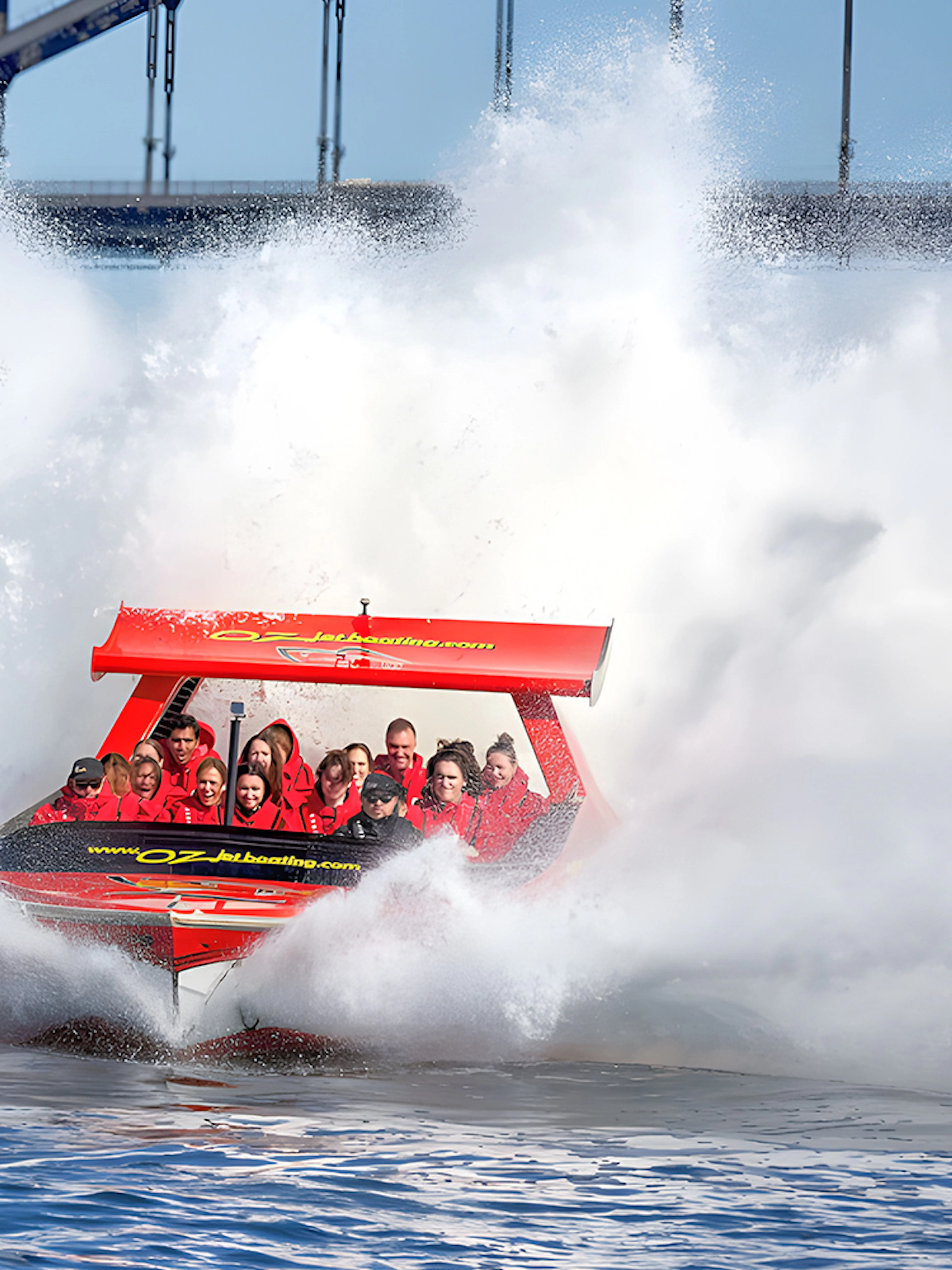 Jet boat splashing through water near Sydney Harbour Bridge with passengers.