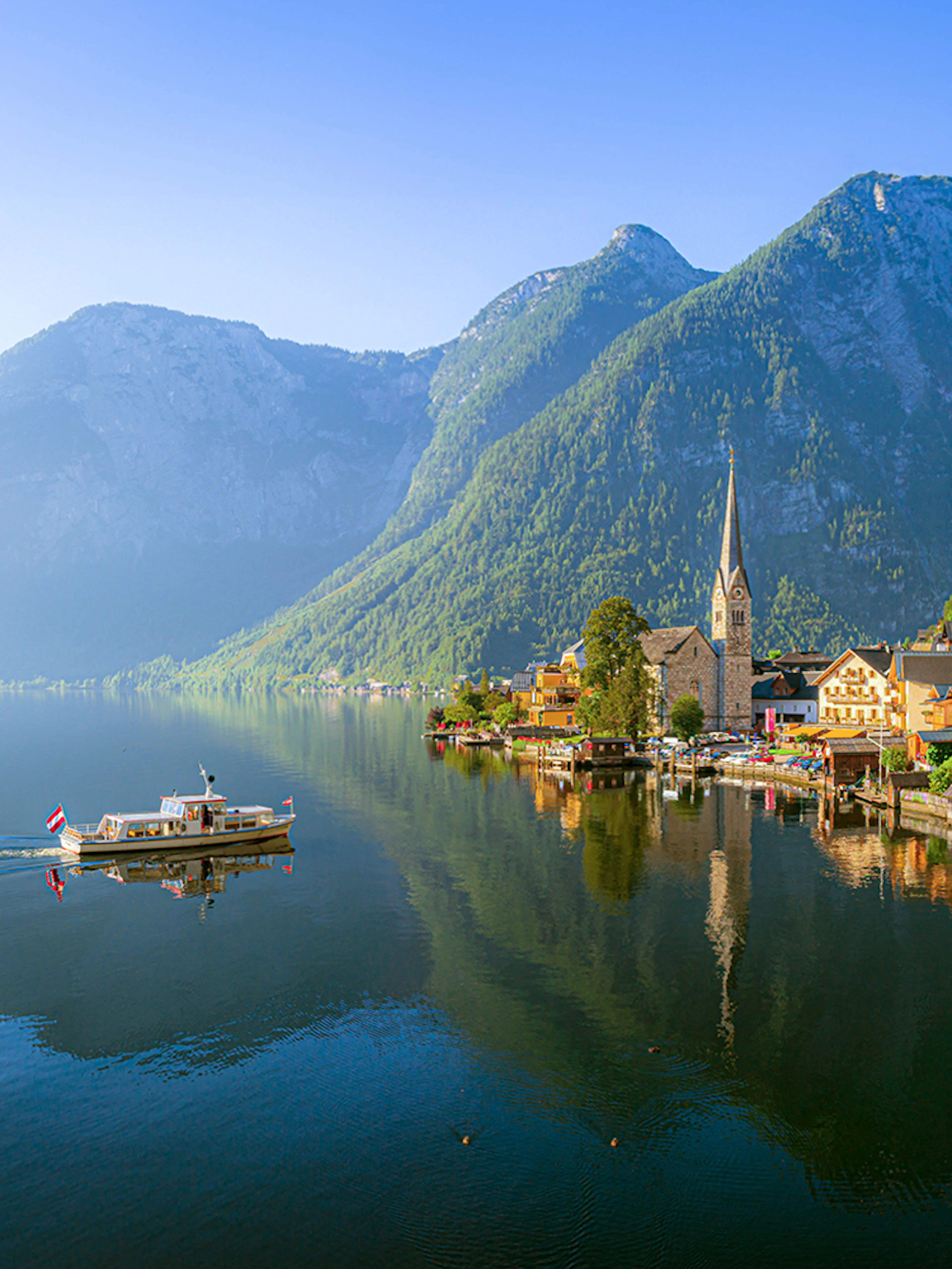Hallstatt village with church and boat on Lake Hallstatt, Austria, viewed from the water.