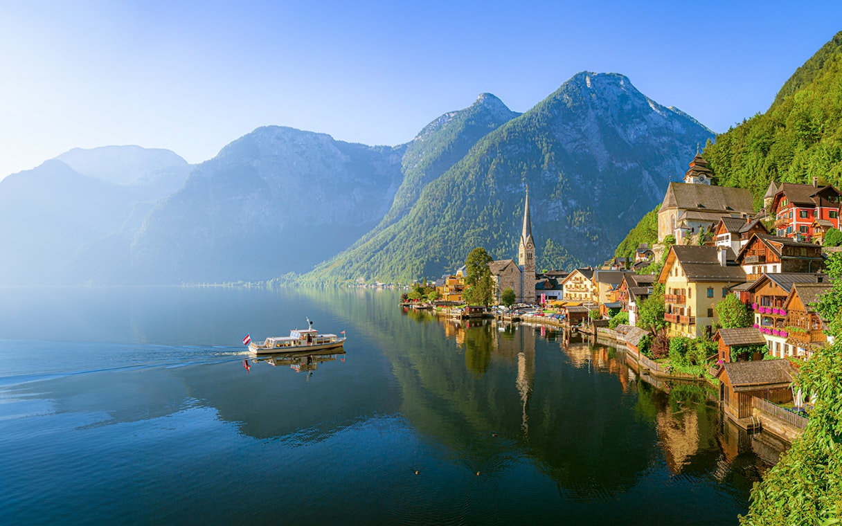 Hallstatt village with church and boat on Lake Hallstatt, Austria, viewed from the water.