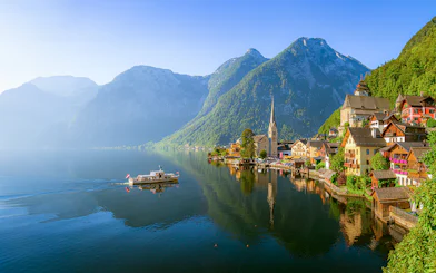Hallstatt village with church and boat on Lake Hallstatt, Austria, viewed from the water.