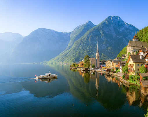 Hallstatt village with church and boat on Lake Hallstatt, Austria, viewed from the water.