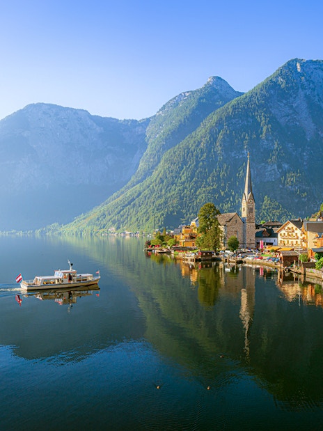 Hallstatt village with church and boat on Lake Hallstatt, Austria, viewed from the water.