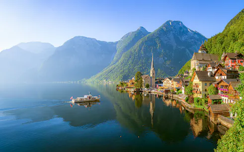 Hallstatt village with church and boat on Lake Hallstatt, Austria, viewed from the water.