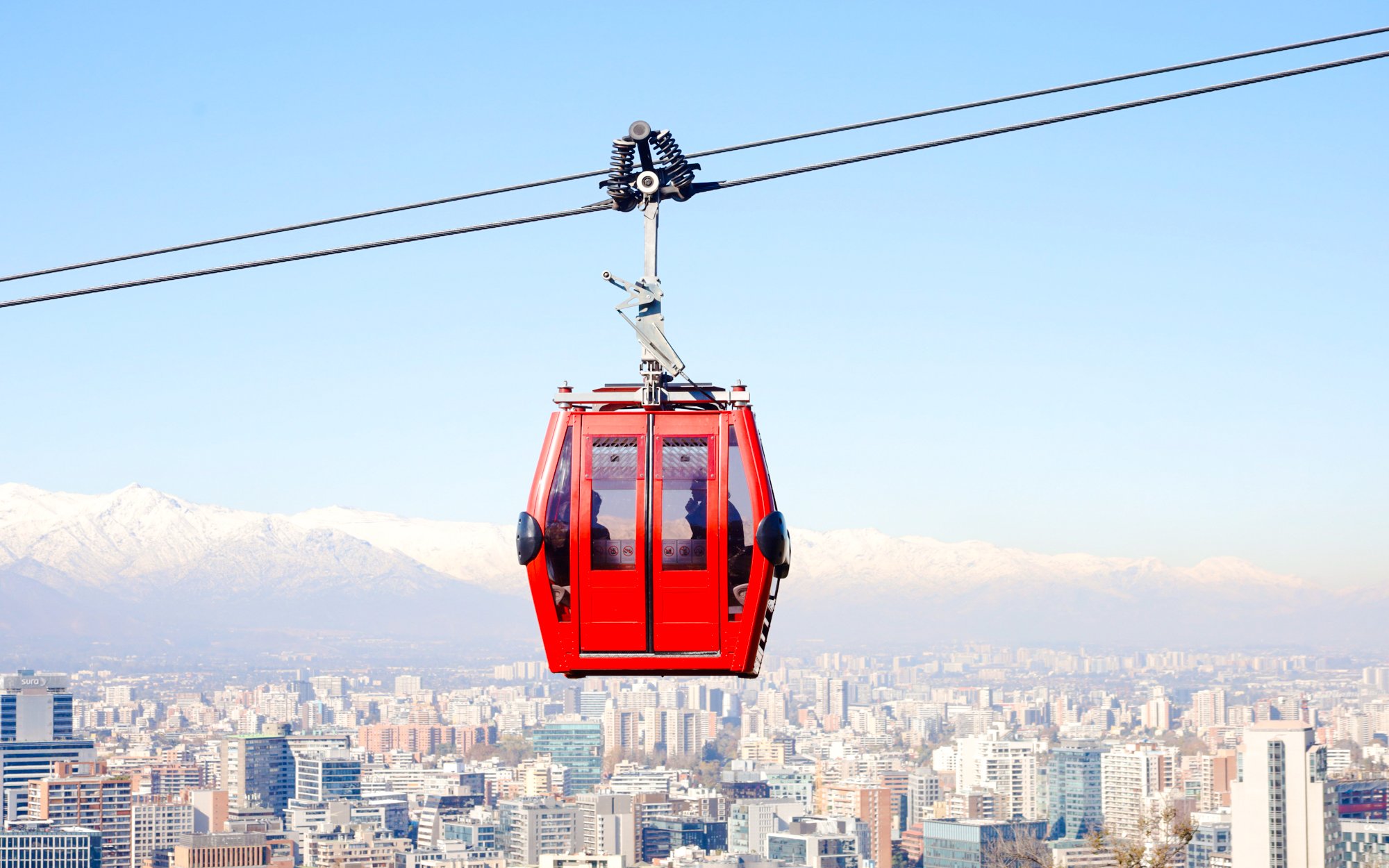 Santiago cable car over cityscape with Andes mountains in the background.