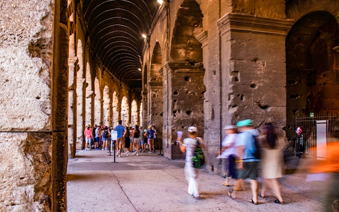 Tourists exploring the interior arches of the Colosseum in Rome, Italy.