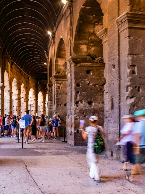 Tourists exploring the interior arches of the Colosseum in Rome, Italy.