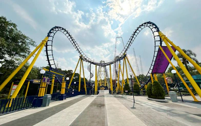 Batgirl roller coaster track at Six Flags Mexico with yellow supports and loops.