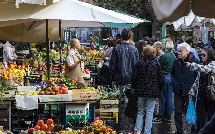 Crowd exploring fresh produce at Rome's San Cosimato Food Market.