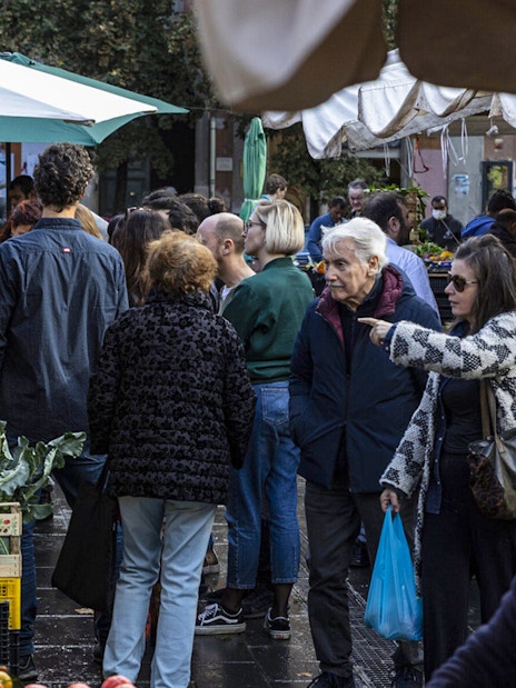 Crowd exploring fresh produce at Rome's San Cosimato Food Market.