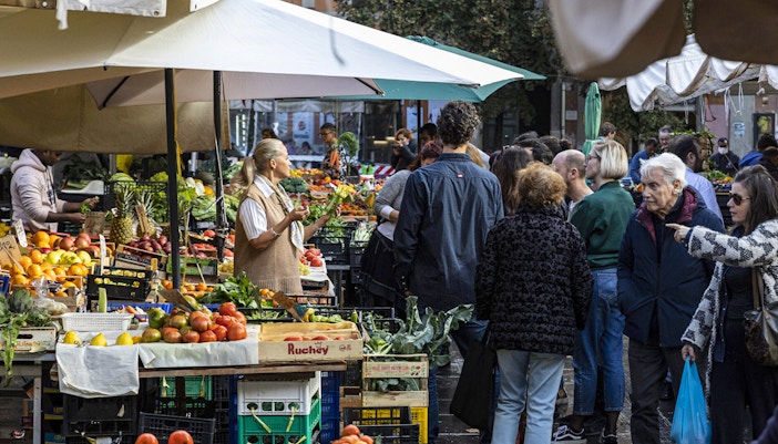 Crowd exploring fresh produce at Rome's San Cosimato Food Market.