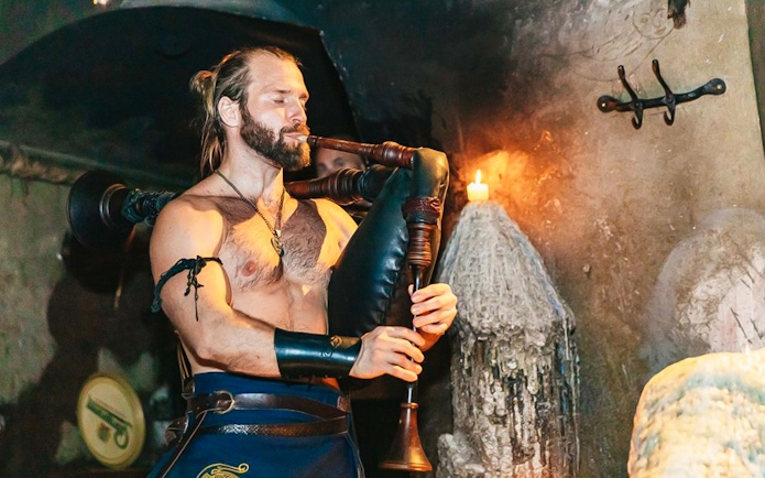 Musician playing bagpipes at a medieval-themed dinner event.