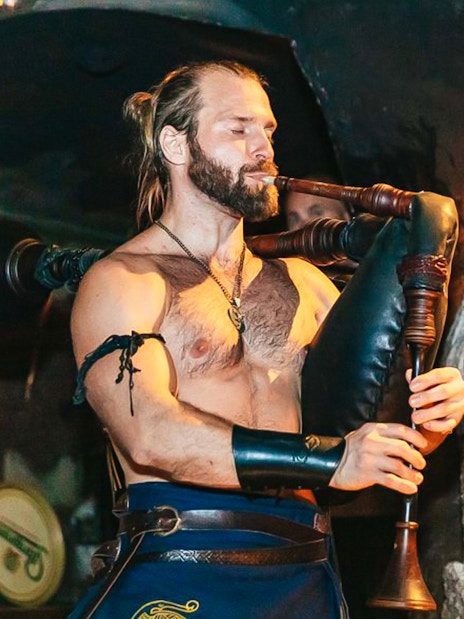 Musician playing bagpipes at a medieval-themed dinner event.