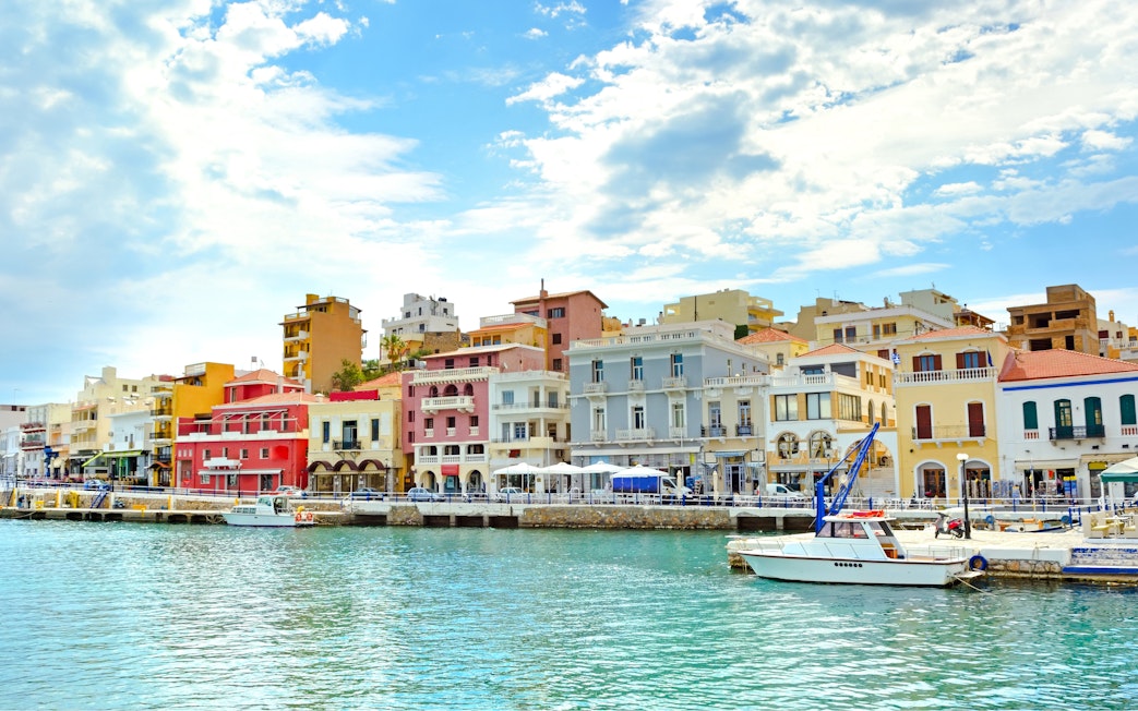 Colorful waterfront buildings in Agios Nikolaos, Corfu, Greece, with a boat docked in the foreground.