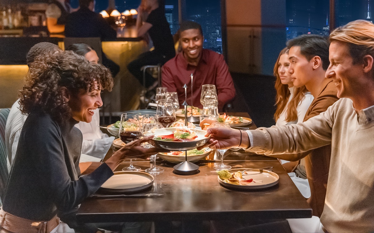 Group dining at One World Observatory with city skyline view.