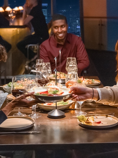 Group dining at One World Observatory with city skyline view.