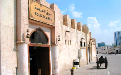 Sharjah's Souk Al Arsah entrance with traditional architecture and a historic cannon.