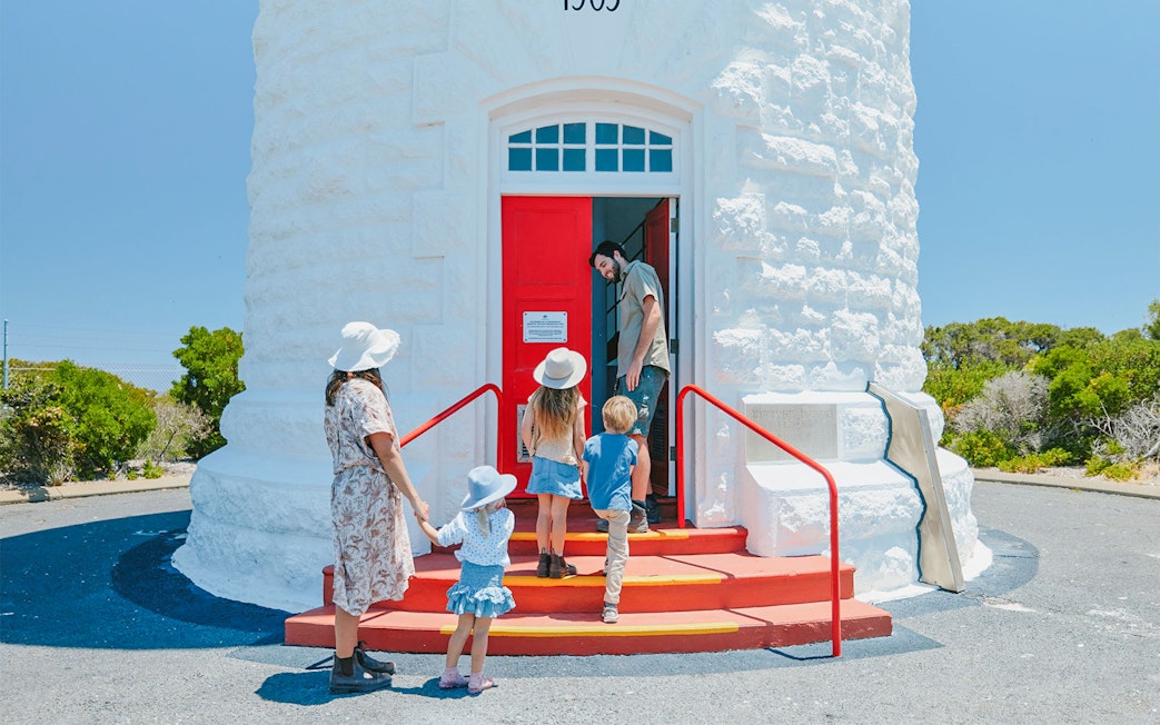 Family entering red door of Cape Naturaliste Lighthouse, "1903" above.