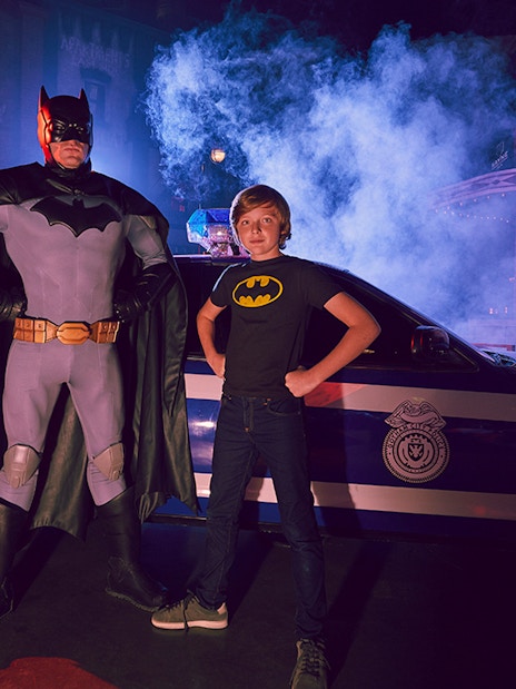 Batman character and child pose in front of police car at Warner Bros. World Abu Dhabi.