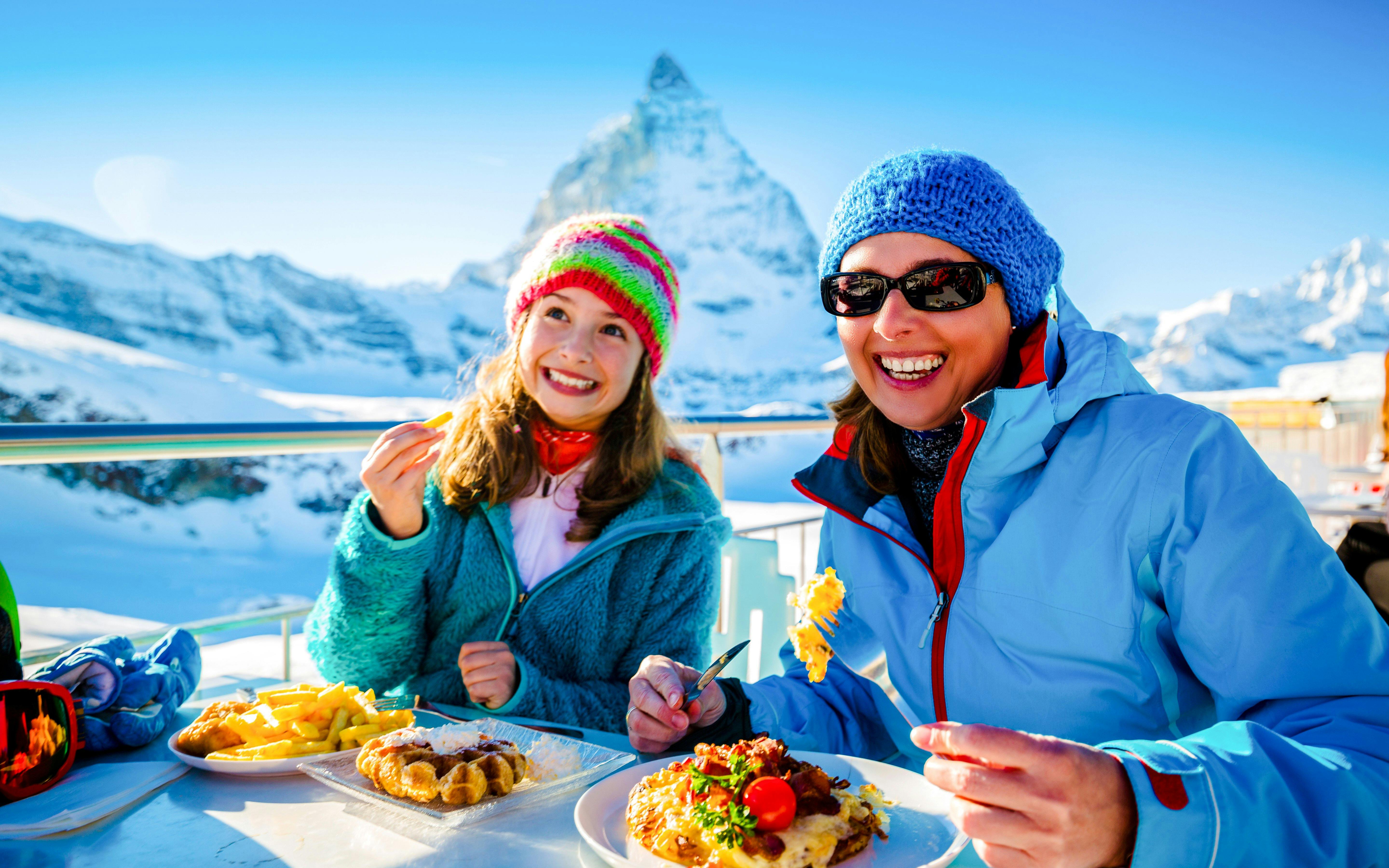 Tourists enjoying Swiss fondue dinner with Matterhorn view in Switzerland.