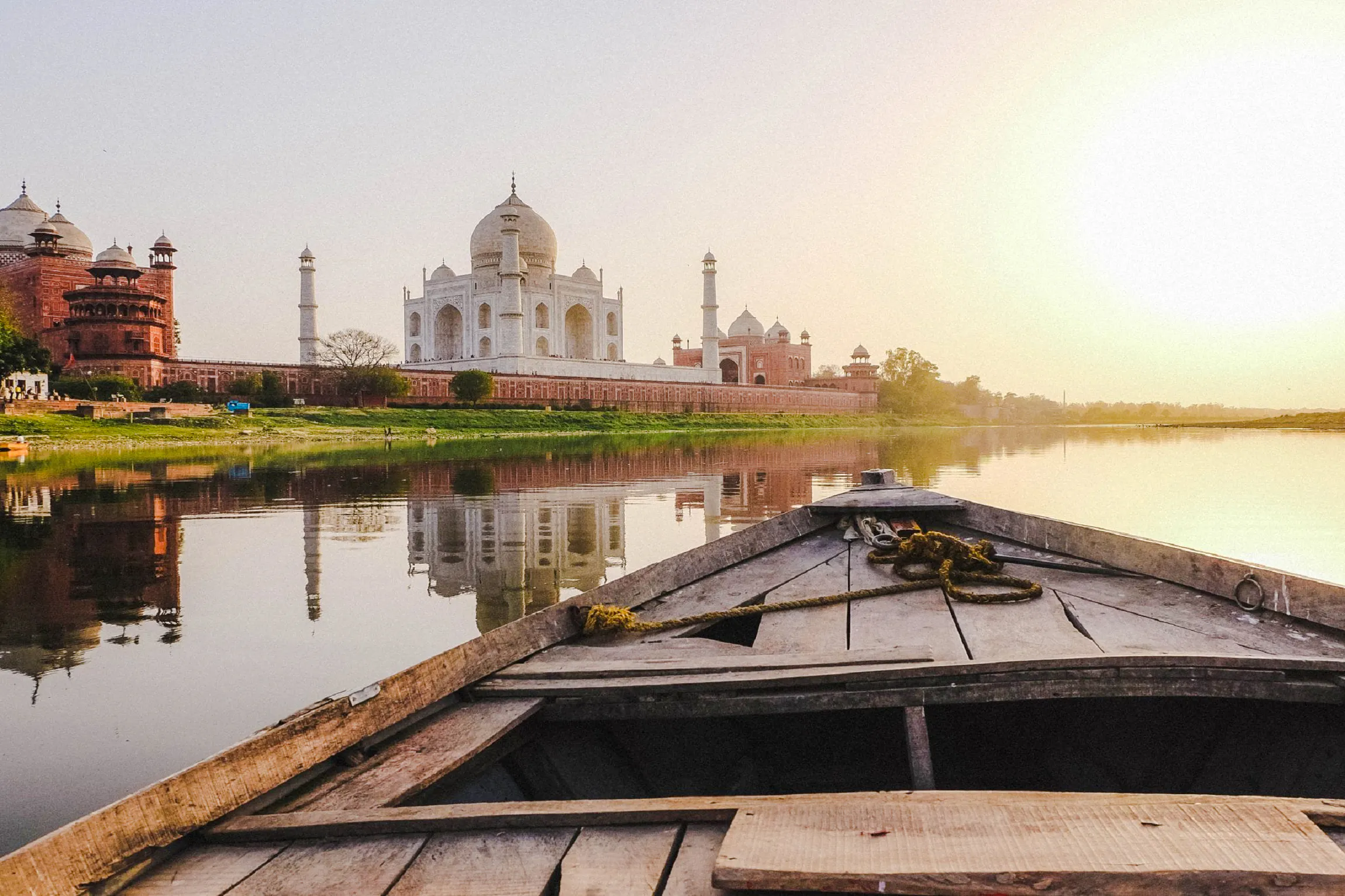 Boat view of the Taj Mahal and riverbank during sunset on Agra heritage tour.