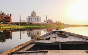 Boat view of the Taj Mahal and riverbank during sunset on Agra heritage tour.