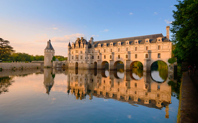 Chenonceau Castle reflecting on the Cher River at sunset, France.