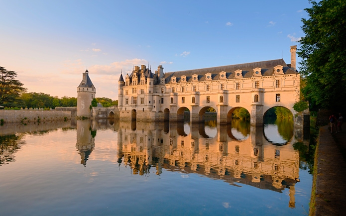 Chenonceau Castle reflecting on the Cher River at sunset, France.